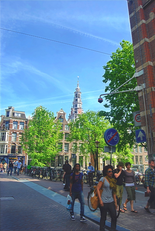 6 - A scenic street view in Amsterdam featuring traditional canal houses and the prominent tower of the Zuiderkerk church